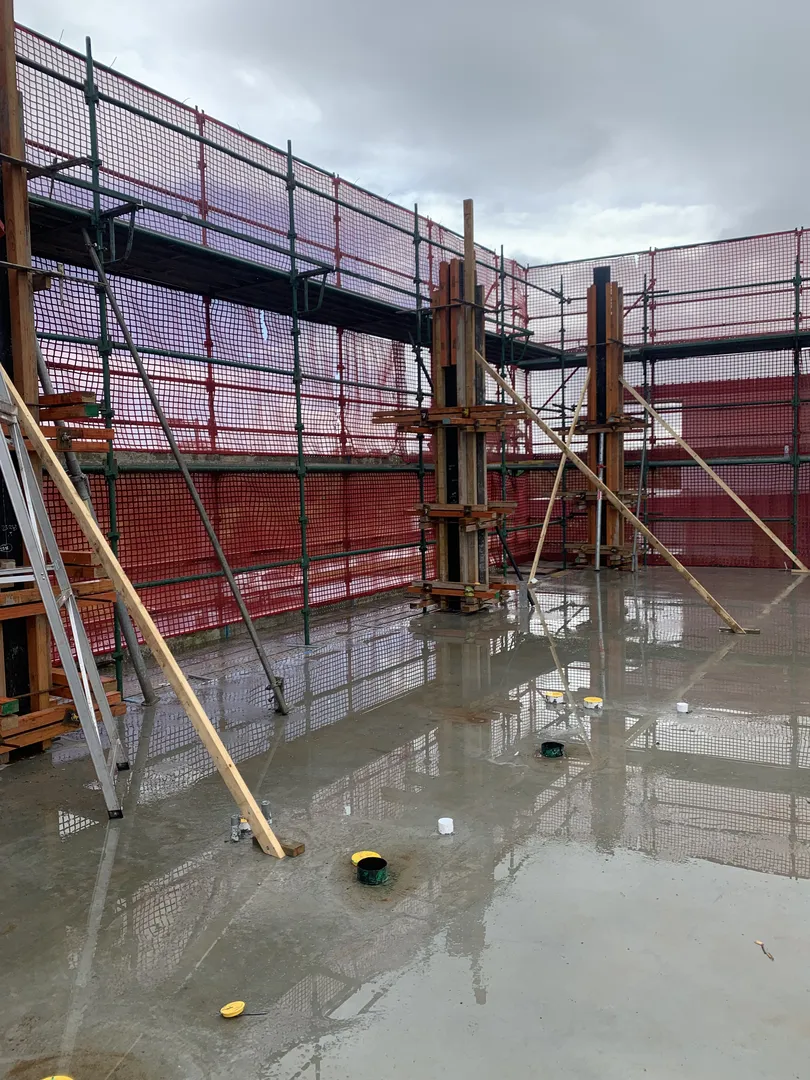 Building site with scaffolding and wet cement floor.