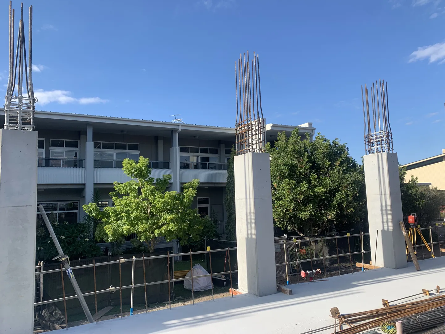 Building construction with steel columns and trees.