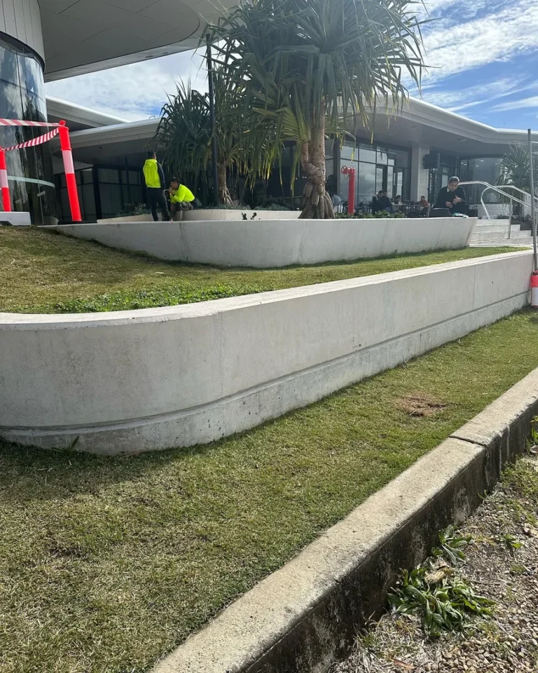 Workers fixing garden at modern building entrance.