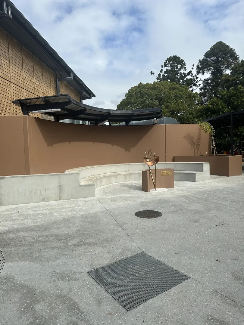 Outdoor cement seating area near a brown wall.