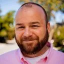 Smiling man with beard in pink shirt