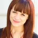 Smiling woman with brown hair and bangs.